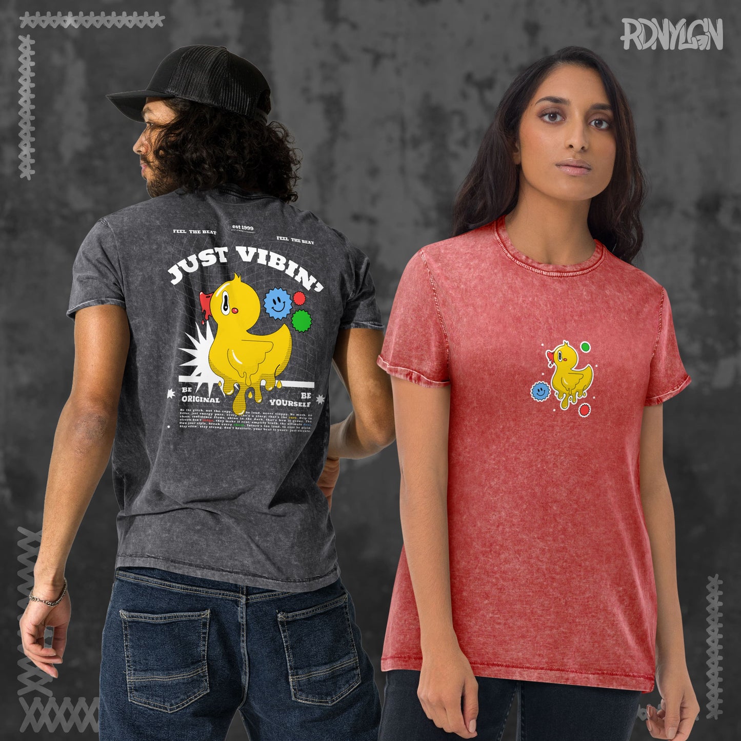 Eine Frau trägt ein rotes Acid-Wash-T-Shirt mit kleinem Entchen vorne. Neben ihr ein Mann mit schwarzem Acid-Wash-T-Shirt, das auf der Rückseite ein großes Entchen-Motiv mit dem Schriftzug „JUST VIBIN’ – Be Yourself“ zeigt.
