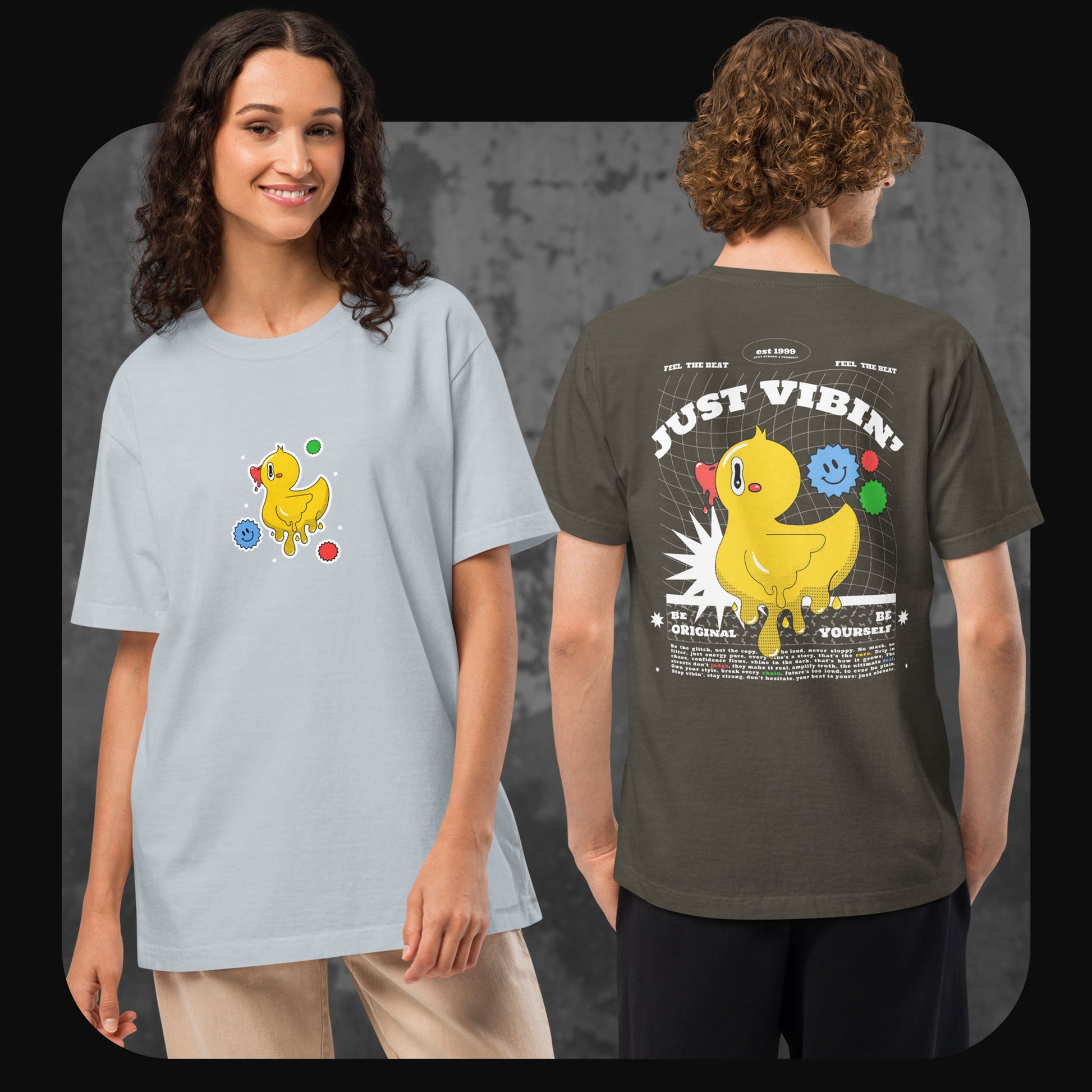 Eine Frau trägt ein hellgraues T-Shirt mit kleiner Frontgrafik einer gelben Cartoon-Ente, daneben ein Mann mit olivgrünem Shirt, Rückendruck „JUST VIBIN’“ und großer Entengrafik.
