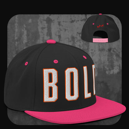 Schwarze Snapback-Cap mit pinker Krempe, pinken Ösen und pinkem Knopf. Auf der Vorderseite „BOLD“ in großen weißen Buchstaben mit oranger Umrandung, hinten kleine pinke Krone.