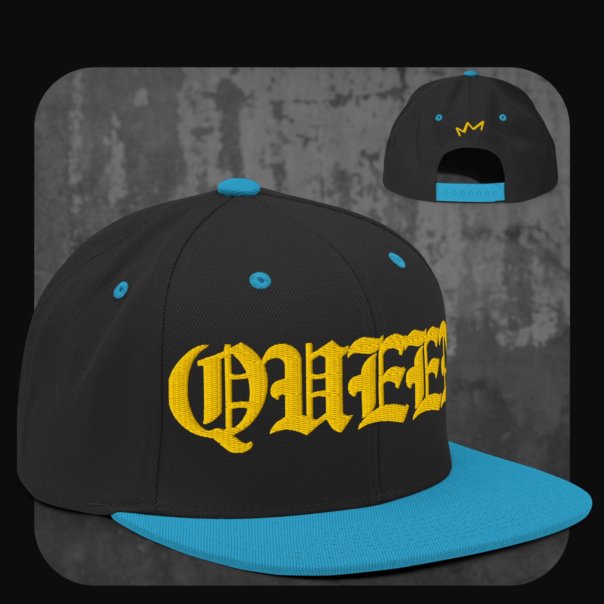 Schwarze Snapback-Cap mit leuchtend blauer Krempe, blauen Ösen und Knopf. Gelber Schriftzug „QUEEN“ in Frakturschrift auf der Vorderseite, gelbe Krone auf der Rückseite.
