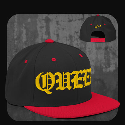 Schwarze Snapback-Cap mit roter Krempe, roten Ösen und rotem Knopf. Vorderseite mit gelbem „QUEEN“-Schriftzug, Rückseite mit gelber Krone.
