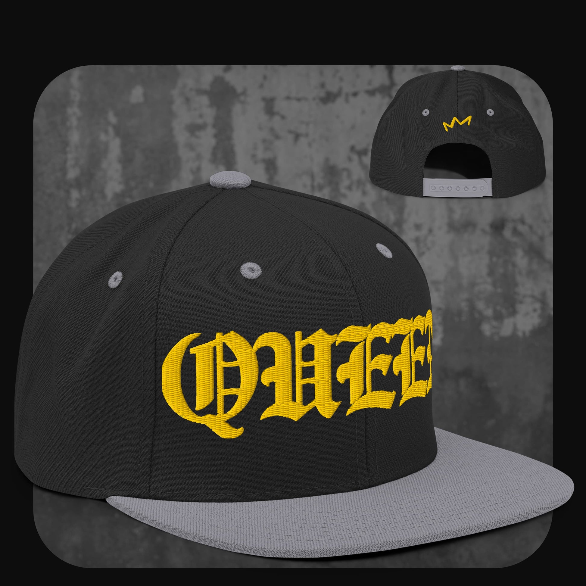 Schwarze Snapback-Cap mit grauer Krempe, grauen Ösen und Knopf. Vorne gelber „QUEEN“-Schriftzug, hinten kleine gelbe Krone.

