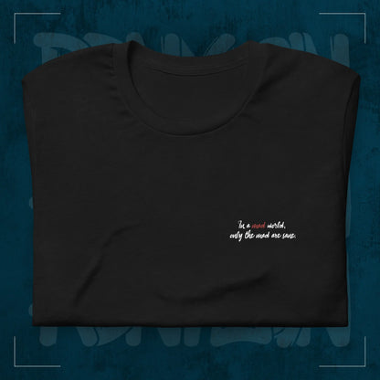 Schwarzes RodneyLogan Regular T-Shirt mit kleinem „Welcome to the Madhouse“-Brustprint als Detailaufnahme auf dunkelblauem Hintergrund.
