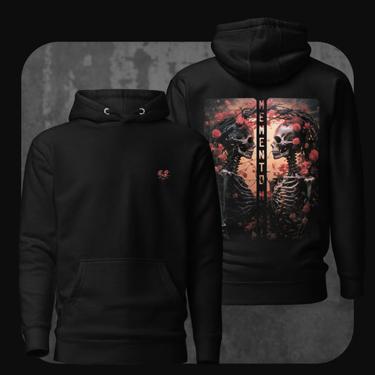 Black hoodie with a minimalist red anatomical heart design on the front. The back features a dramatic illustration of two skeletons facing each other, surrounded by roses, with the words ‘MEMENTO MORI’ vertically between them.
