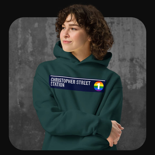Model wearing a green hoodie with a “Christopher Street Station” patch and a rainbow-colored number 1 subway icon across the chest.